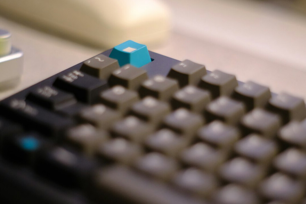 Hands typing on a laptop keyboard with a notebook nearby